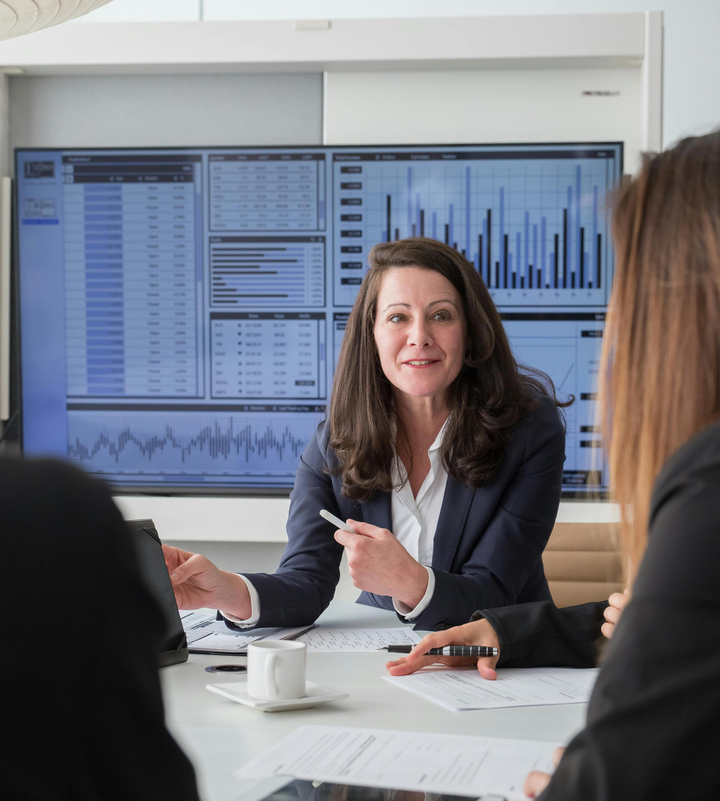 Mujer explicando resultados de dashboard que tiene detrás de ella Explicación de optimización de procesos