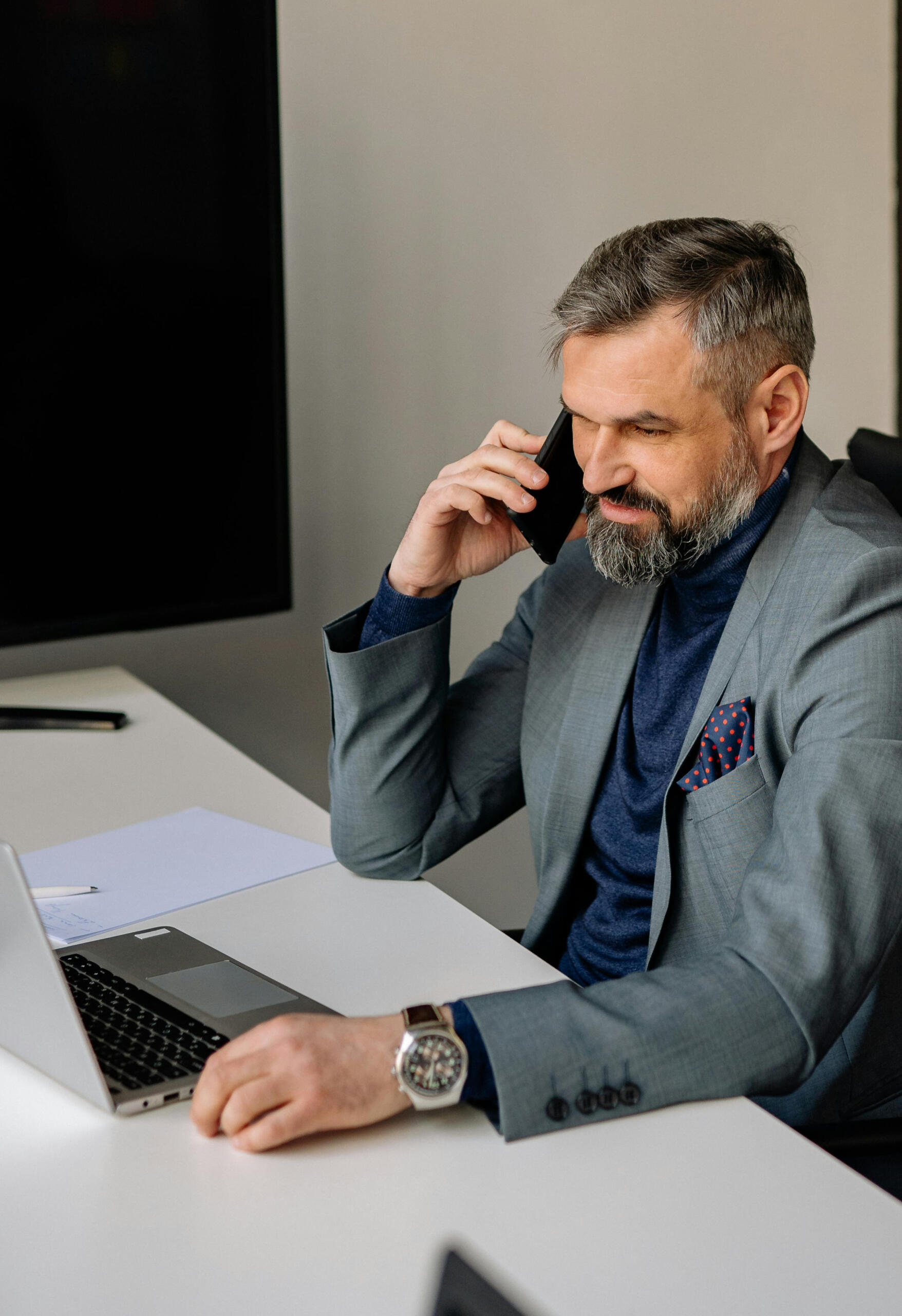 Ejecutivo haciendo llamada mientras observa su dashboard y se muestra contento por resultados positivos